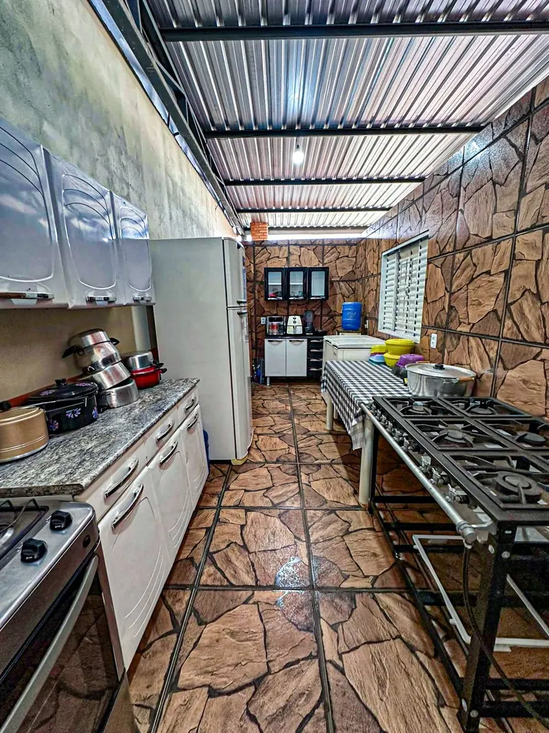 Cozinha toda montada, com bancada de granito. Segundo a cliente: dois freezers/geladeiras, fogão a gás, fogão industrial, micro-ondas, AirFryer, bebedor de água com água mineral, panelas e talheres